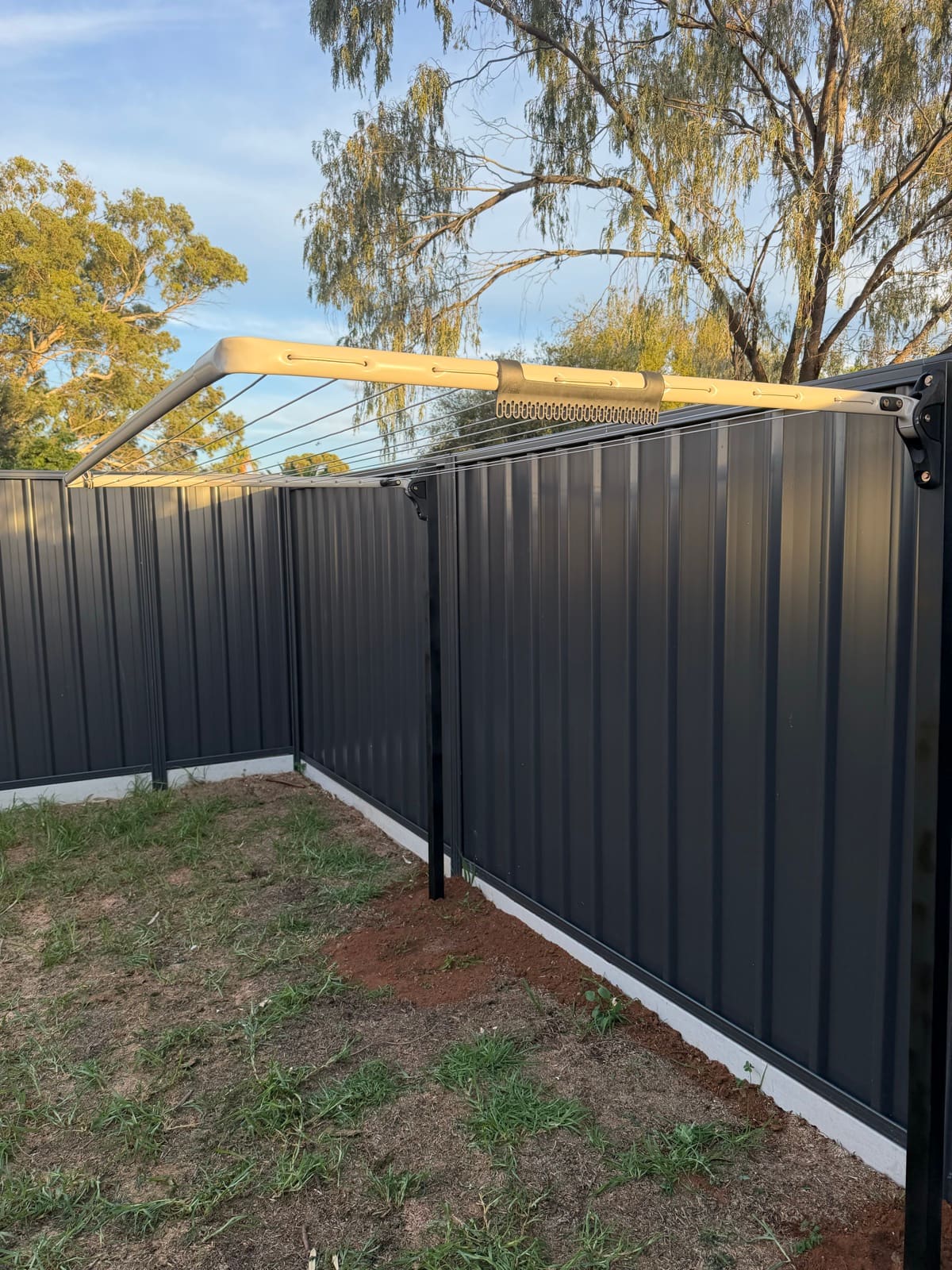 Fold-down clothesline installed on black posts in front of a charcoal corrugated fence in Adelaide