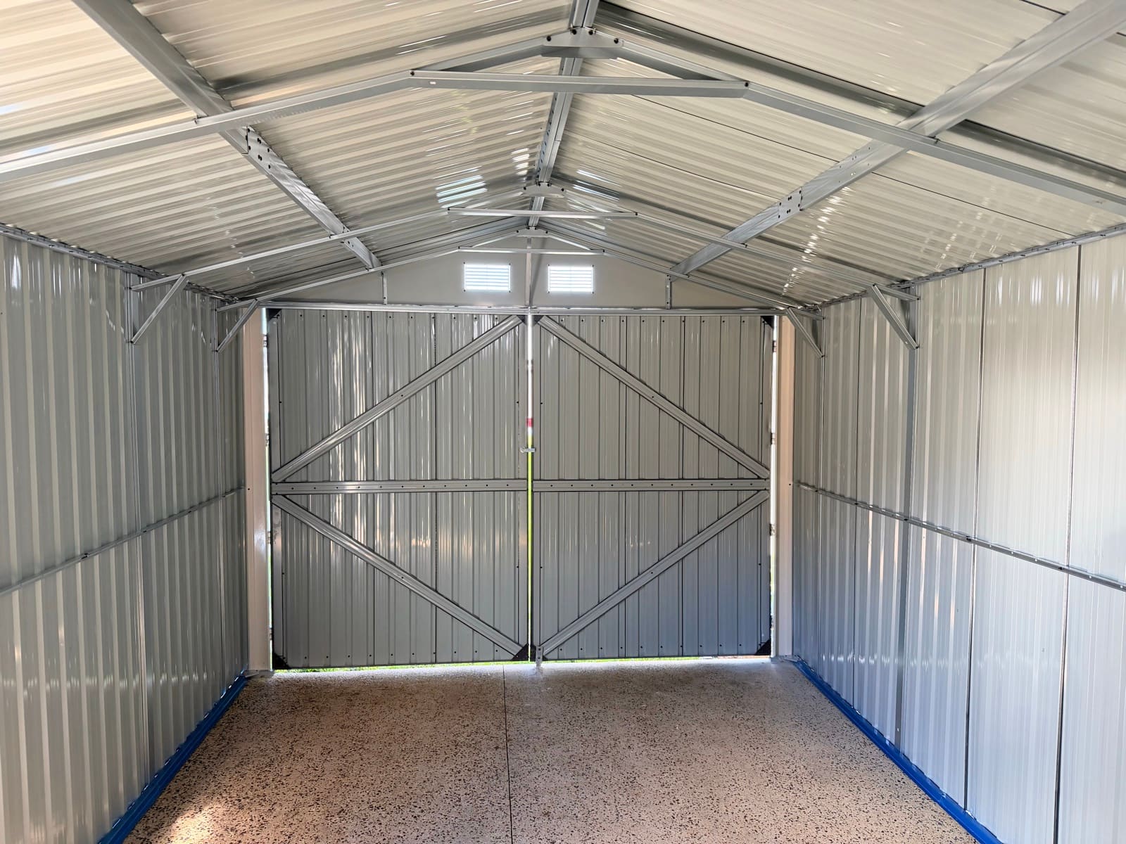 Interior of a newly installed metal garden shed with corrugated walls and concrete slab floor in Adelaide