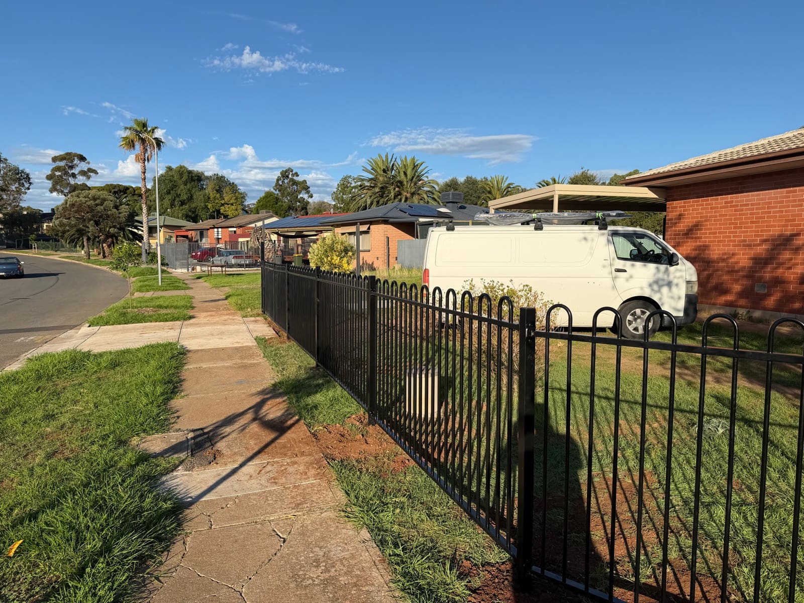 Black tubular hoop-top fence freshly installed along a residential sidewalk and front lawn in Adelaide