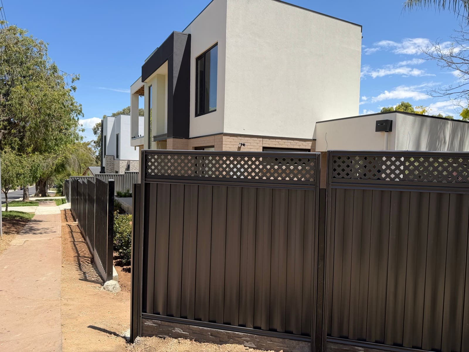 Dark charcoal metal fence with lattice top and stone-look base along a modern Adelaide home