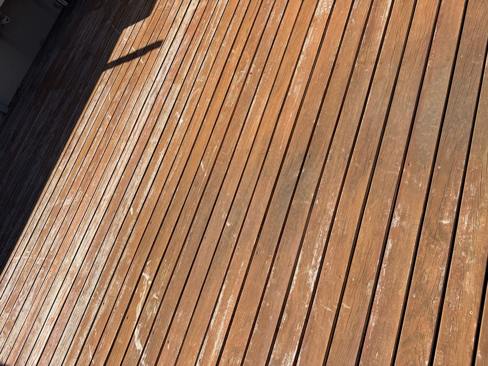 Close-up of weathered timber deck boards with peeling stain before deck restoration in Adelaide