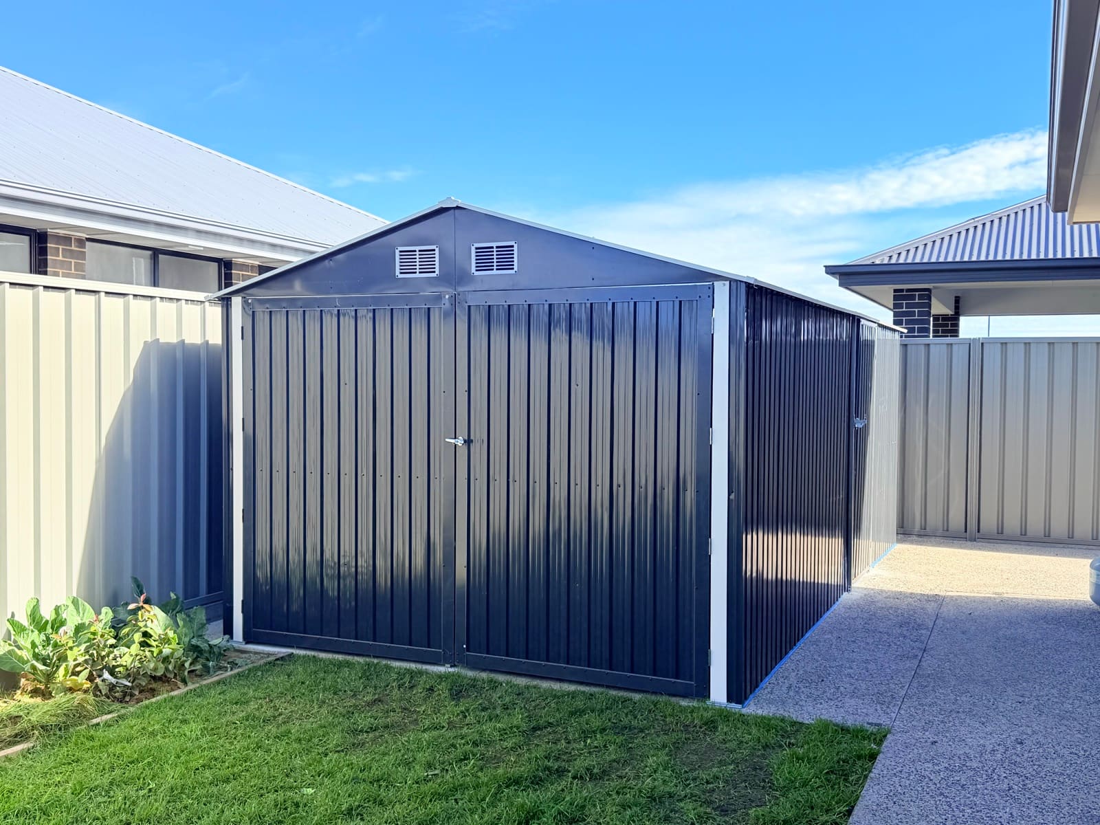 Completed dark charcoal metal garden shed with white trim in an Adelaide backyard