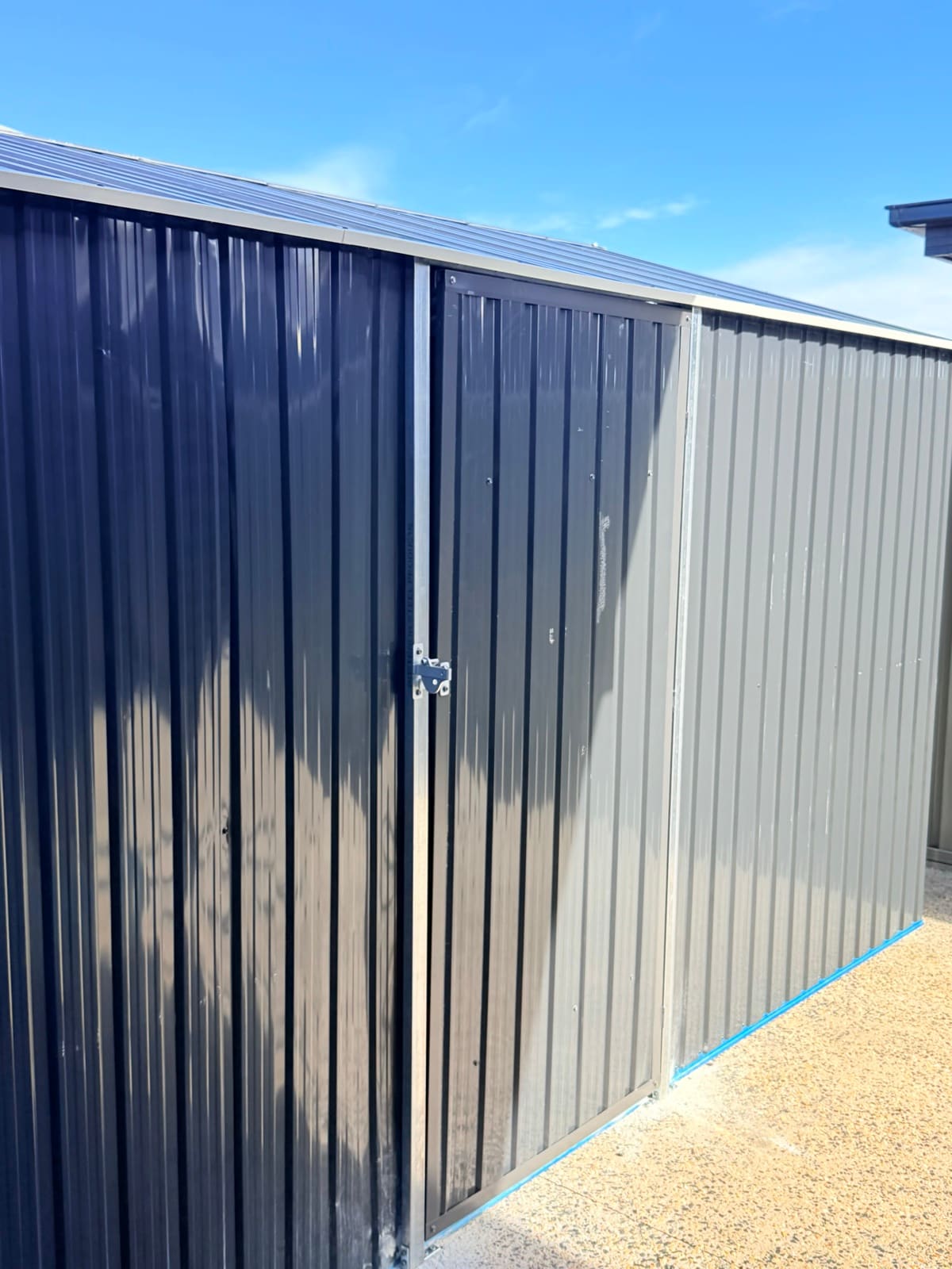 Side detail of corrugated metal shed panels and door latch
